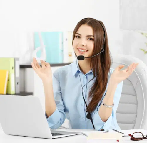 Friendly virtual receptionist with headset gesturing while assisting a customer at her desk