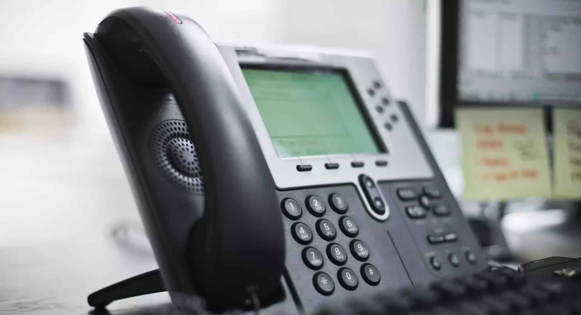 From Switchboard to Virtual Receptionist Close-up of an office telephone switchboard with a digital screen, keypad, and handset, symbolizing the transition from a traditional switchboard to a virtual receptionist system.