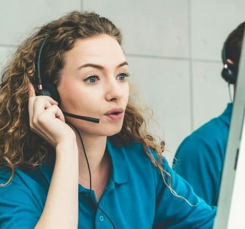 Customer service representative speaking on a headset while monitoring a screen, representing forwarding lines to a virtual receptionist.