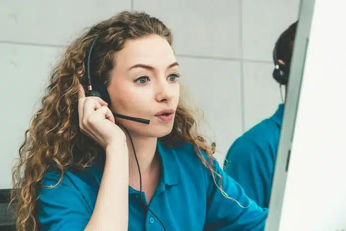 Customer service representative speaking on a headset while monitoring a screen, representing forwarding lines to a virtual receptionist.