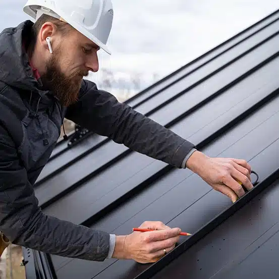 Roofer measuring metal panel—ideal time to use a roofers answering service or virtual receptionist.