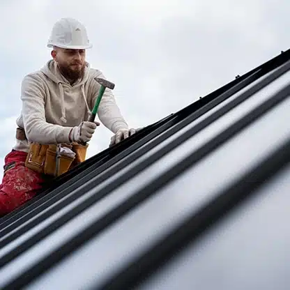 Roofer on rooftop with hammer—shows when a virtual receptionist for roofers can handle calls.