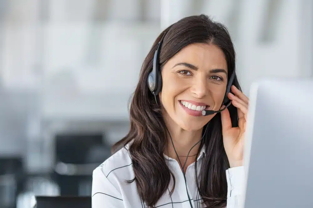 Smiling bilingual intake specialist wearing a headset while assisting clients, highlighting the importance of language support for law firms.