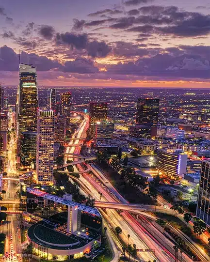 Los Angeles city lights at night with highways and tall buildings.