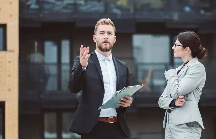 A real estate agent discussing market insights with a businesswoman, highlighting real estate market trends.