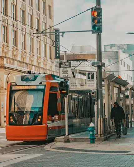A METRO light rail passing through downtown Houston with traffic signals.