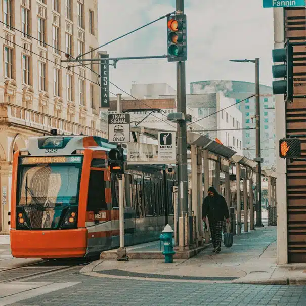 A METRO light rail passing through downtown Houston with traffic signals.