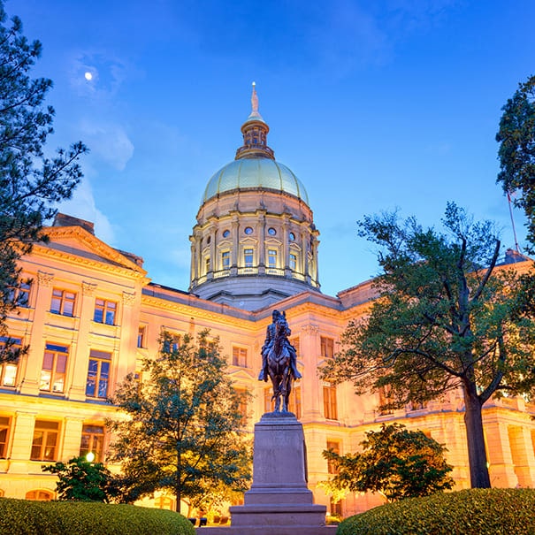 Georgia State Capitol building in Atlanta illuminated at dusk with a equestrian statue in the foreground.