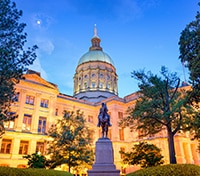 Georgia State Capitol building in Atlanta illuminated at dusk with a equestrian statue in the foreground.