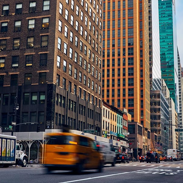 Busy city street in New York with yellow cabs and towering buildings.