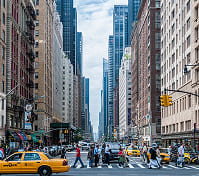 Bustling New York City street with pedestrians crossing and taxis driving.