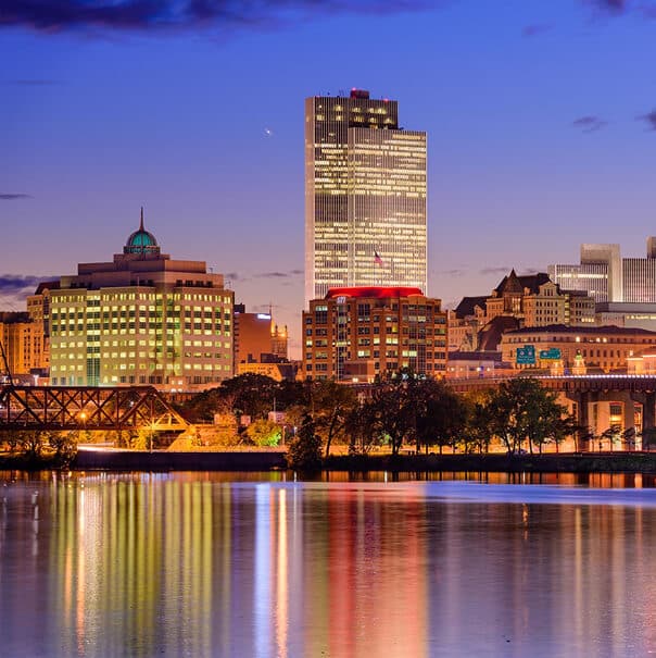 Albany city skyline at night, reflecting in the river.