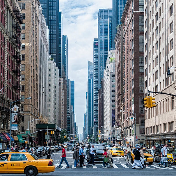 Bustling New York City street with pedestrians crossing and taxis driving.