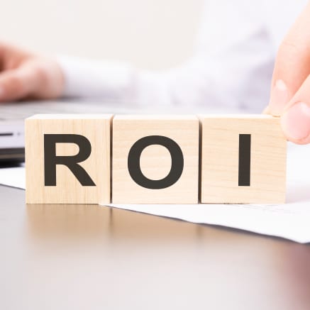 Wooden blocks spelling ROI on desk with papers, representing virtual receptionist return on investment