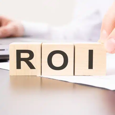 Wooden blocks spelling ROI on desk with papers, representing virtual receptionist return on investment