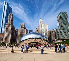 Visitors at the Cloud Gate sculpture in Millennium Park with Chicago buildings behind