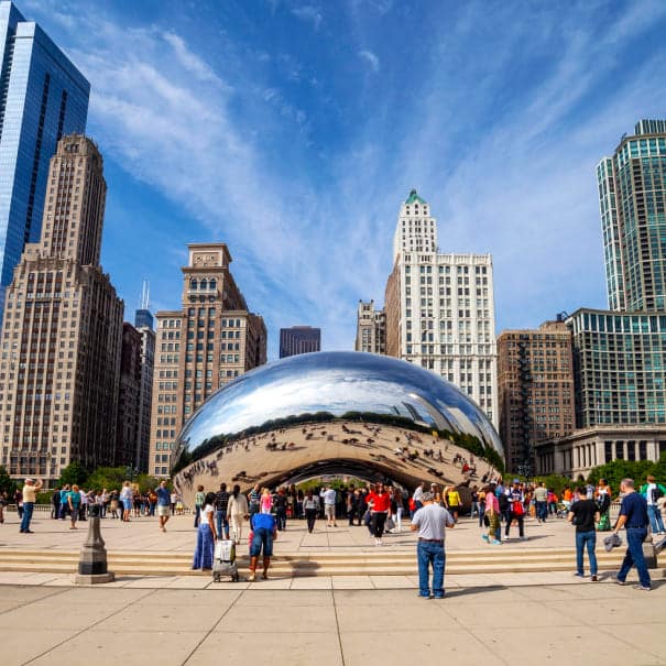 Visitors at the Cloud Gate sculpture in Millennium Park with Chicago buildings behind