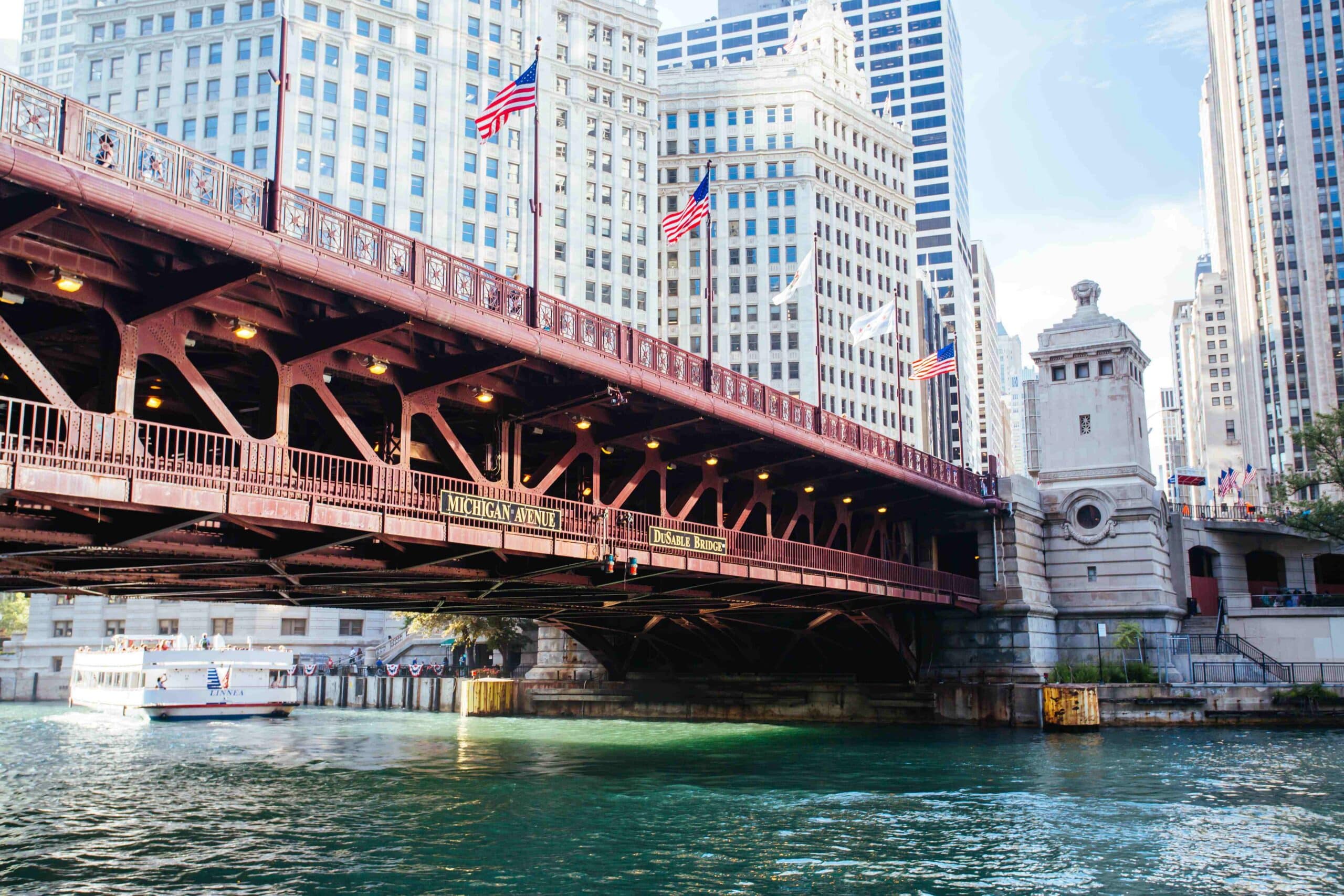 Steel bascule bridge with American flags over the Chicago River, downtown buildings behind