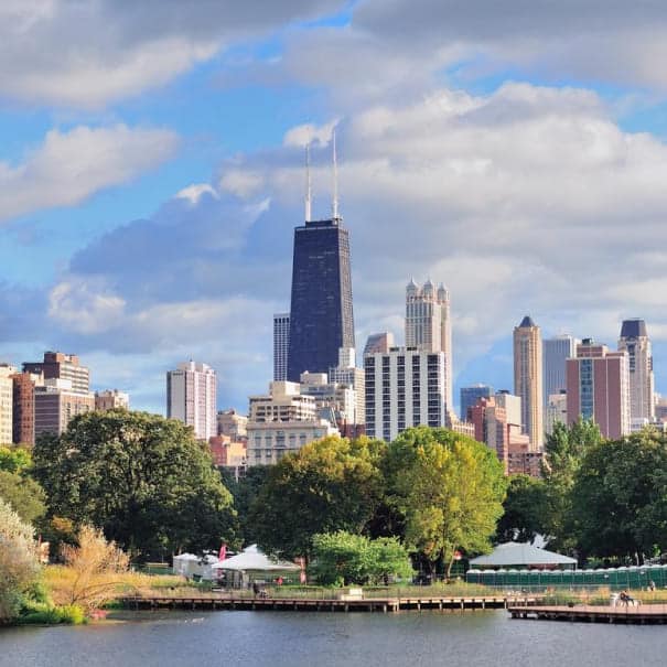 Chicago skyline rising above trees and a waterfront on a sunny day